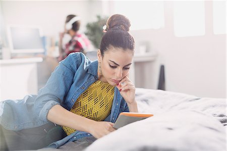 Young woman using digital tablet on bed Stock Photo - Premium Royalty-Free, Code: 6113-08568571