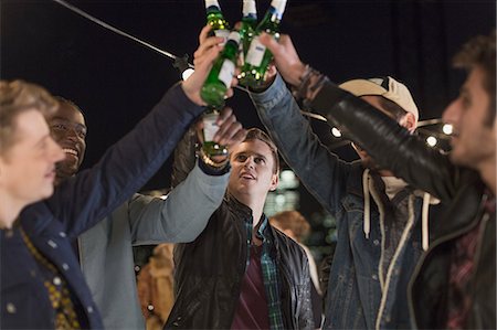 simsearch:614-06169404,k - Young men toasting beer bottles at party Photographie de stock - Premium Libres de Droits, Code: 6113-08568779