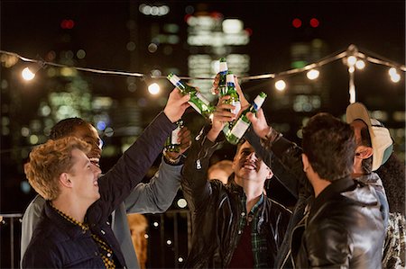 string lights fun - Young men toasting beer bottles at rooftop party Stock Photo - Premium Royalty-Free, Code: 6113-08568793
