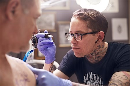 Focused tattoo artist preparing tattoo gun Foto de stock - Sin royalties Premium, Código: 6113-08521271
