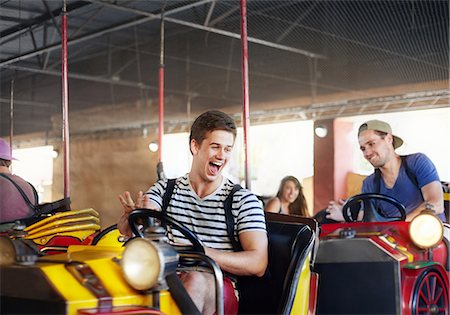 simsearch:6113-08521335,k - Laughing young men riding bumper cars at amusement park Stock Photo - Premium Royalty-Free, Code: 6113-08521355