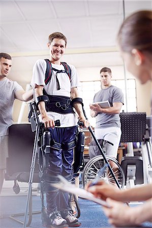 simsearch:6113-08521465,k - Smiling man with forearm crutches in physical therapy Foto de stock - Royalty Free Premium, Número: 6113-08521470