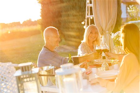 santé! - Senior couple an adult daughter toasting wine glasses at sunny patio table Photographie de stock - Premium Libres de Droits, Code: 6113-08521542