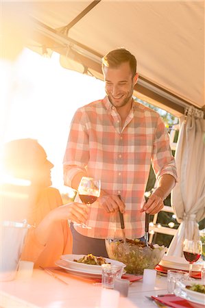 Young man serving salad to wife drinking wine at sunny patio table Foto de stock - Sin royalties Premium, Código: 6113-08521549