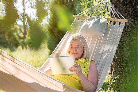 simsearch:6122-07705331,k - Senior woman using digital tablet and relaxing in summer hammock Stock Photo - Premium Royalty-Free, Code: 6113-08521551