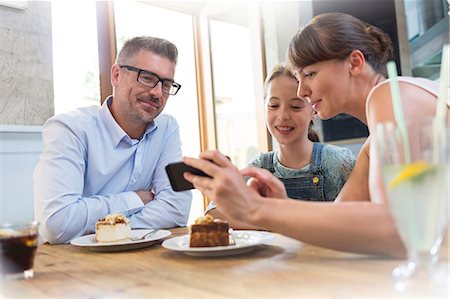 smile couple taking picture phone - Family with cell phone eating dessert at cafe table Stock Photo - Premium Royalty-Free, Code: 6113-08521585