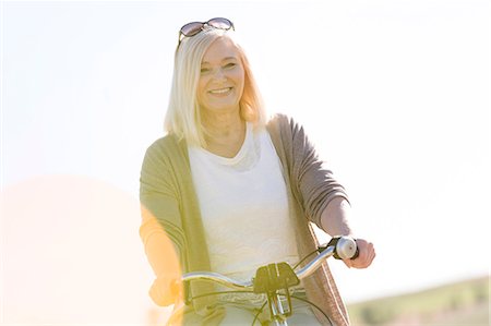 sunny portrait of woman one person looking at camera - Portrait smiling senior woman bike riding Photographie de stock - Premium Libres de Droits, Code: 6113-08521526