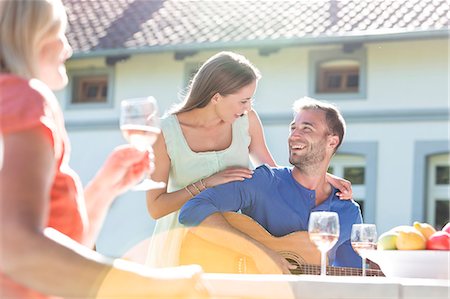 Smiling young couple playing guitar and drinking wine on sunny patio Photographie de stock - Premium Libres de Droits, Code: 6113-08521536