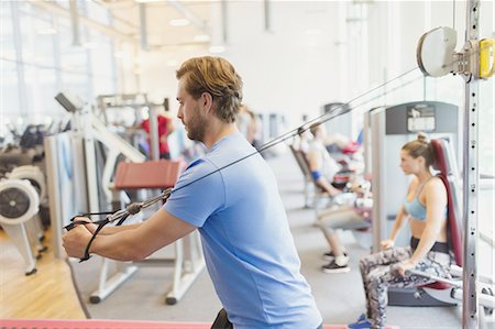 simsearch:6113-08536097,k - Man using cable exercise equipment at gym Stock Photo - Premium Royalty-Free, Code: 6113-08536076