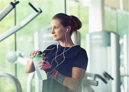 simsearch:6113-08536110,k - Woman with headphones resting and drinking water at gym Stock Photo - Premium Royalty-Free, Code: 6113-08536079