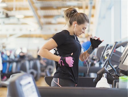 female jogger side view - Woman running on treadmill at gym with headphones Stock Photo - Premium Royalty-Free, Code: 6113-08536006