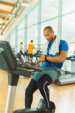 Man checking smart watch on exercise bike at gym Foto de stock - Sin royalties Premium, Código: 6113-08536164