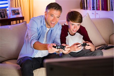 family playing game inside - Father and son playing video game in living room Stock Photo - Premium Royalty-Free, Code: 6113-08655389