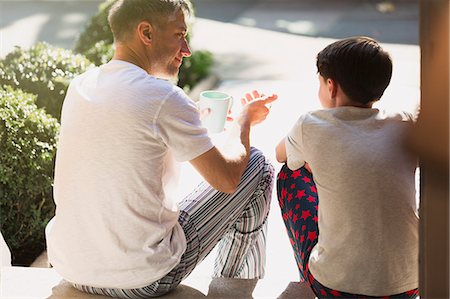 pyjamas (sleepwear with pants) - Father with coffee talking to son on front stoop Stock Photo - Premium Royalty-Free, Code: 6113-08655404