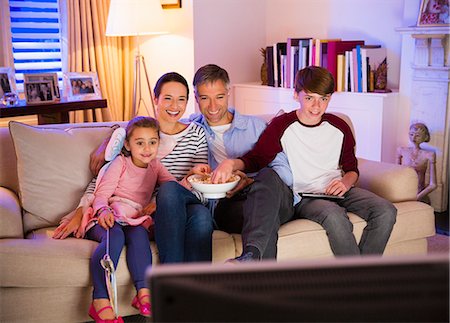 simsearch:6113-08909960,k - Family eating popcorn and watching TV in living room Stock Photo - Premium Royalty-Free, Code: 6113-08655423