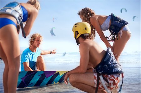 Man teaching friends kiteboarding on sunny beach Photographie de stock - Premium Libres de Droits, Code: 6113-08655557