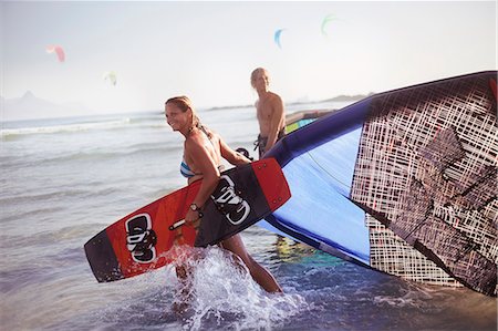 Couple pulling kiteboarding equipment into ocean surf Foto de stock - Sin royalties Premium, Código: 6113-08655558