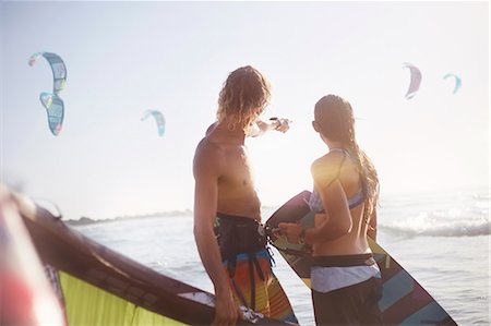 Couple watching kiteboarders over sunny ocean Stock Photo - Premium Royalty-Free, Code: 6113-08655561