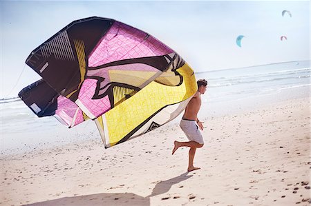 Man running with kiteboarding kite on sunny beach Foto de stock - Sin royalties Premium, Código: 6113-08655581