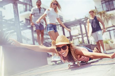 simsearch:6113-08882733,k - Portrait playful young woman laying riding skateboard on sunny boardwalk Stock Photo - Premium Royalty-Free, Code: 6113-08655591