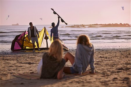 Women watching men preparing to kiteboard on beach Stock Photo - Premium Royalty-Free, Code: 6113-08655522