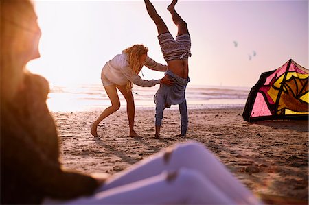 Woman holding man doing handstand on sunset beach Foto de stock - Sin royalties Premium, Código: 6113-08655530