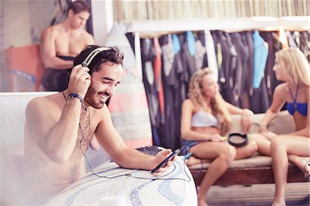 surfboard mobile - Smiling surfer listening to music with headphones and mp3 player Stock Photo - Premium Royalty-Free, Code: 6113-08655536