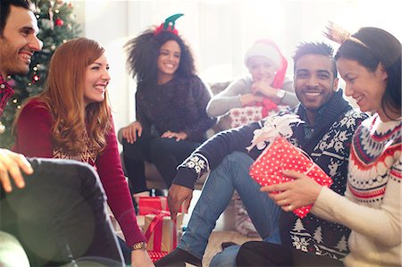 fête - Friends opening Christmas gifts in living room Photographie de stock - Premium Libres de Droits, Code: 6113-08659578