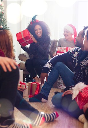 simsearch:6113-08659572,k - Friends opening Christmas gifts in living room Stock Photo - Premium Royalty-Free, Code: 6113-08659579