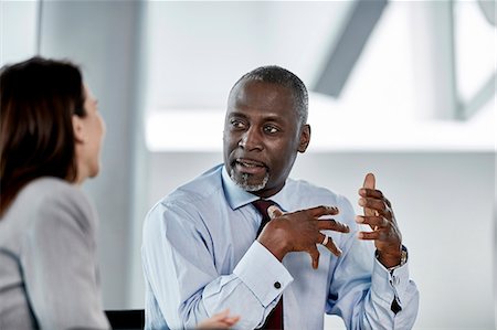 real people in office - Businessman explaining to businesswoman in meeting Stock Photo - Premium Royalty-Free, Code: 6113-08659653