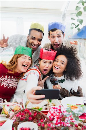 fun dinner - Silly friends in paper crowns taking selfie at Christmas dinner Foto de stock - Sin royalties Premium, Código: 6113-08659603