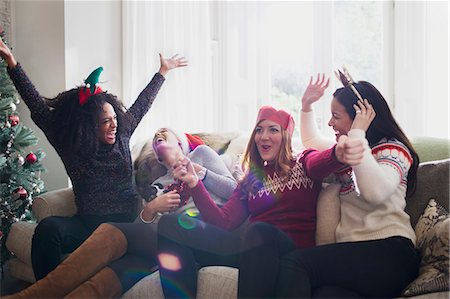 Laughing friends celebrating Christmas on sofa Stock Photo - Premium Royalty-Free, Code: 6113-08659602