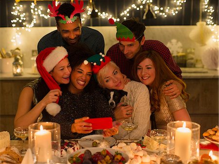 Playful friends with dog taking selfie at candlelight Christmas table Photographie de stock - Premium Libres de Droits, Code: 6113-08659610