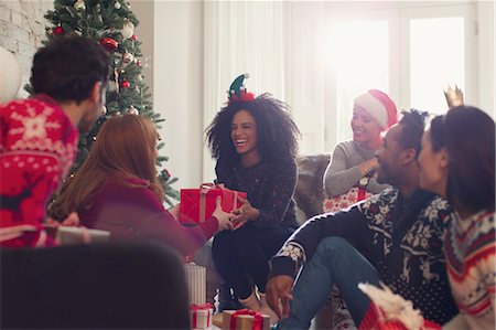 día de fiesta - Smiling friends exchanging Christmas gifts in living room Foto de stock - Sin royalties Premium, Código: 6113-08659616