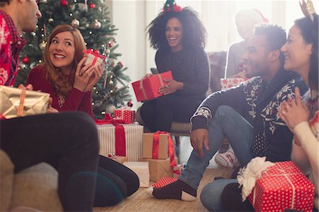 party in lounge - Friends watching playful woman shaking Christmas gift Stock Photo - Premium Royalty-Free, Code: 6113-08659618