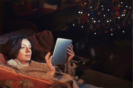 Woman using digital tablet relaxing on sofa in living room near Christmas tree Foto de stock - Sin royalties Premium, Código: 6113-08698062