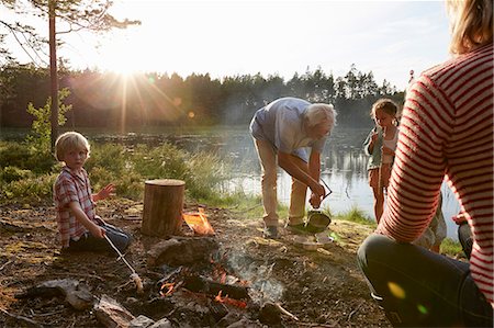 simsearch:614-08982841,k - Grandparents and grandchildren at campfire at sunny lakeside in woods Photographie de stock - Premium Libres de Droits, Code: 6113-08698069
