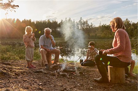 Grandparents and grandchildren enjoying campfire at sunny lakeside Stock Photo - Premium Royalty-Free, Code: 6113-08698080