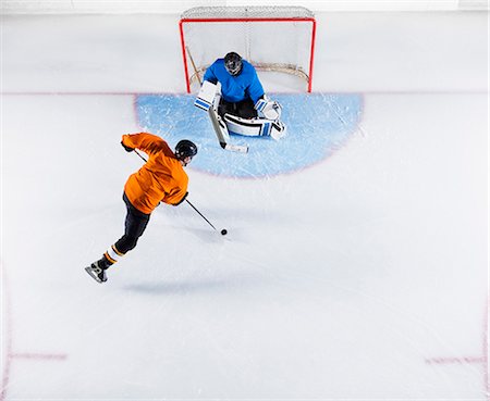 Hockey player shooting the puck at goal net Foto de stock - Royalty Free Premium, Número: 6113-08698169