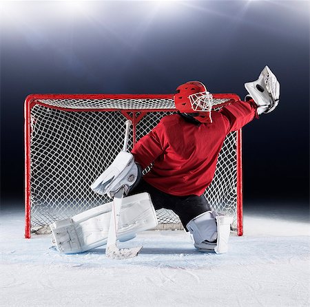 para - Hockey goalie in red uniform reaching for puck with glove at goal net Photographie de stock - Premium Libres de Droits, Code: 6113-08698186