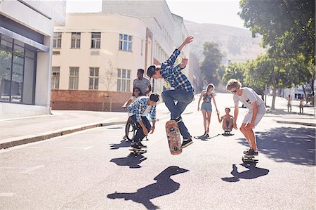 skate stunts - Teenage friends skateboarding on sunny urban street Stock Photo - Premium Royalty-Free, Code: 6113-08698252