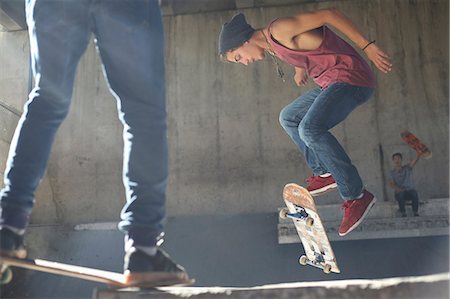 Teenage boy flipping skateboard at skate park Foto de stock - Sin royalties Premium, Código: 6113-08698201