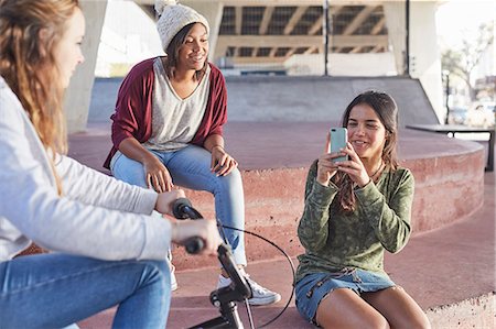 Teenage girls using camera phone at skate park Photographie de stock - Premium Libres de Droits, Code: 6113-08698225