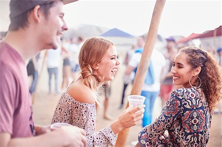 simsearch:6113-07564759,k - Young friends laughing and drinking at music festival Photographie de stock - Premium Libres de Droits, Code: 6113-08698301