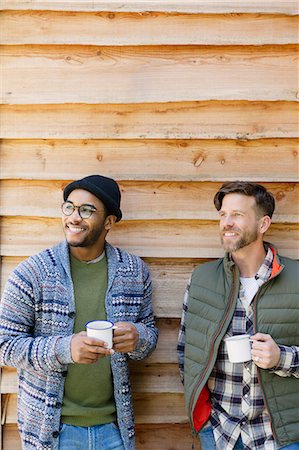 Smiling men drinking coffee outside cabin Stock Photo - Premium Royalty-Free, Code: 6113-08743446