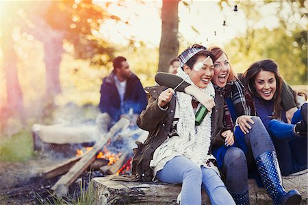 simsearch:6113-06908609,k - Friends laughing roasting marshmallows at campfire Photographie de stock - Premium Libres de Droits, Code: 6113-08743453