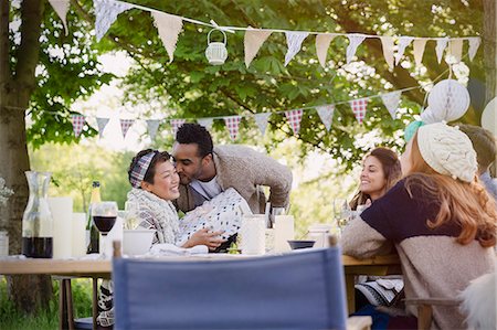 Boyfriend kissing girlfriend with birthday gift at garden party table Foto de stock - Sin royalties Premium, Código: 6113-08743488