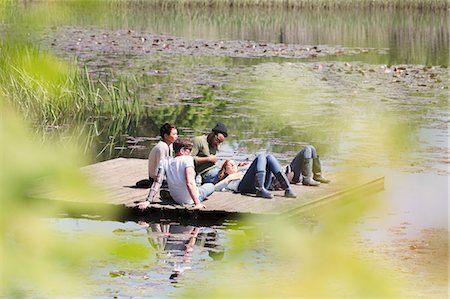 simsearch:6113-08743427,k - Friends laying and relaxing on sunny dock at lakeside Photographie de stock - Premium Libres de Droits, Code: 6113-08743411