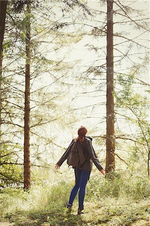 simsearch:6113-09239818,k - Woman with backpack looking up at trees in sunny woods Stock Photo - Premium Royalty-Free, Code: 6113-08743541