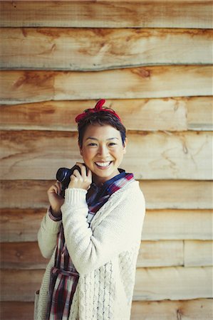 Portrait smiling woman with camera outside cabin Stock Photo - Premium Royalty-Free, Code: 6113-08743578